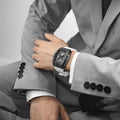 Close-up of a model wearing the TB8210CF Passion Red men’s tonneau watch, featuring a tonneau stainless steel case, a carbon fiber bezel, and white strap. The Seiko Epson automatic movement is displayed with a tourbillon at 9 o’clock, a power reserve indicator at 12 o’clock, and a 24-hour display at 6 o’clock.
