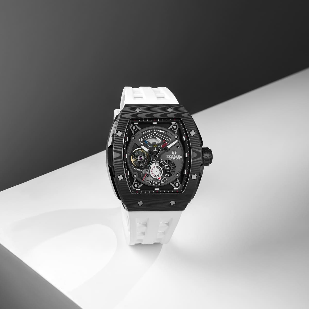 Close-up of a model wearing the TSAR BOMBA Elemental TB8210CF Elite White men’s tonneau watch, featuring a tonneau stainless steel case, a carbon fiber bezel, and white strap. The Seiko Epson automatic movement is displayed with a tourbillon at 9 o’clock, a power reserve indicator at 12 o’clock, and a 24-hour display at 6 o’clock.
