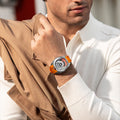 Close-up of a model wearing the TSAR BOMBA Reactor TB8213 staless steel Automatic Interchangeable Men's Watch. Features a sliver stainless steel case and bezel, powered by a Japanese automatic movement. Top dial: minutes; central dial: seconds. Bottom main display: hour hand = pointer reading + central window reading. The TB8213 utilizes the TSAR BOMBA interchangeable module system, allowing for quick and tool-free changes of the strap, bezel, and crown.orange strap
