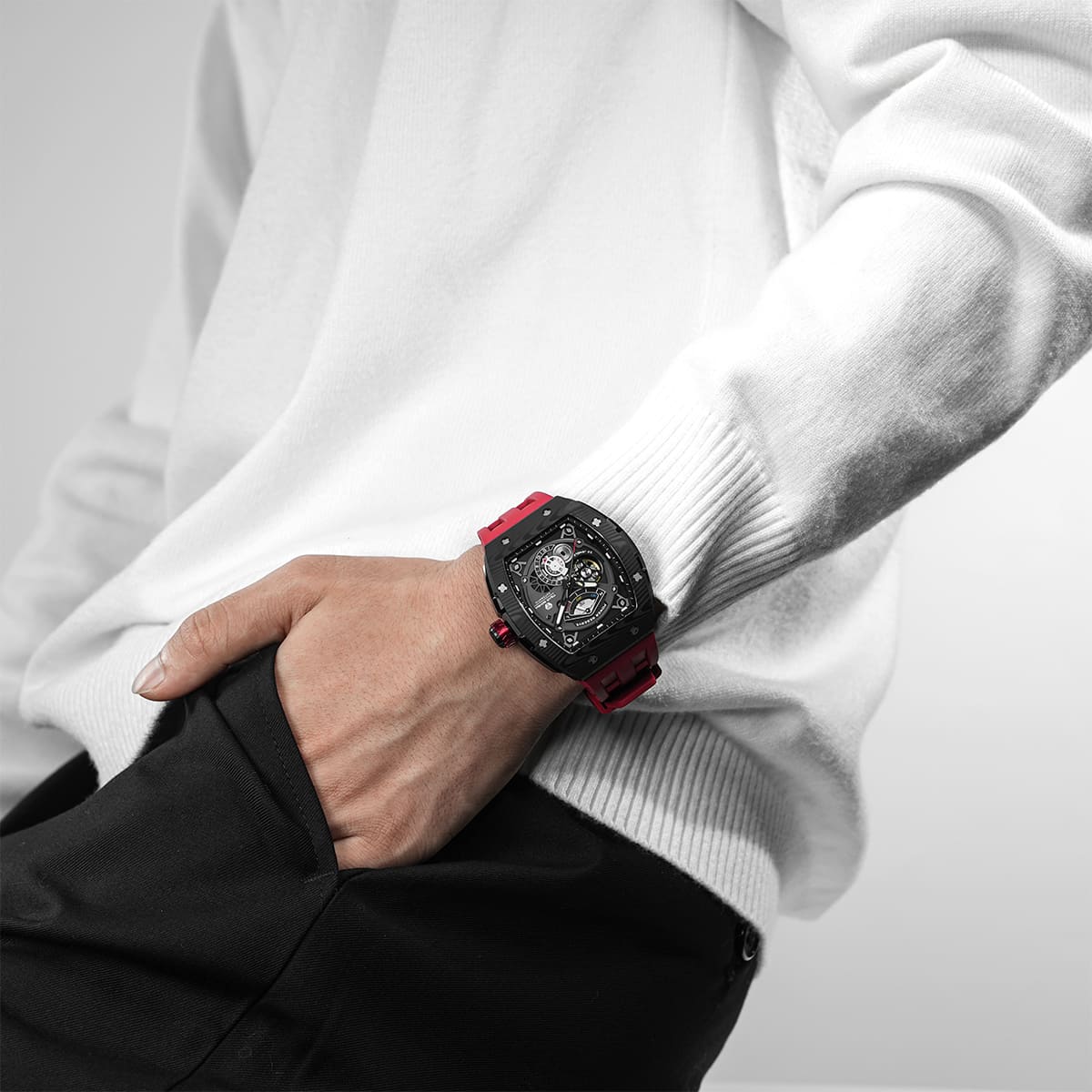 Close-up of a model wearing the TSAR BOMBA Elemental TB8210CF Passion Red men’s tonneau watch, featuring a tonneau stainless steel case, a carbon fiber bezel, and red strap. The Seiko Epson automatic movement is displayed with a tourbillon at 9 o’clock, a power reserve indicator at 12 o’clock, and a 24-hour display at 6 o’clock.