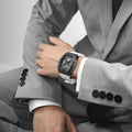 The TSAR BOMBA elemental TB8210CF automatic tourbillon tonneau-shaped watch features a carbon fiber bezel and a stainless steel case, powered by a Seiko Epson automatic movement. The tonneau-shaped case is paired with a skeletonized dial and a power reserve indicator.--Model wearing display